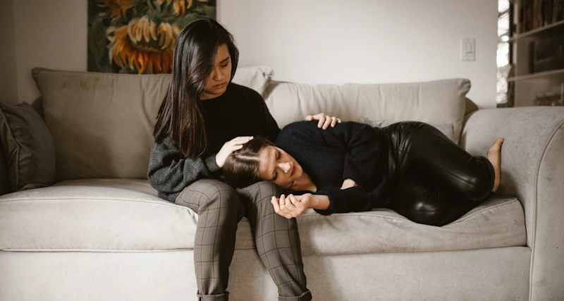 A girl comforting an emotionally distressed woman on a couch